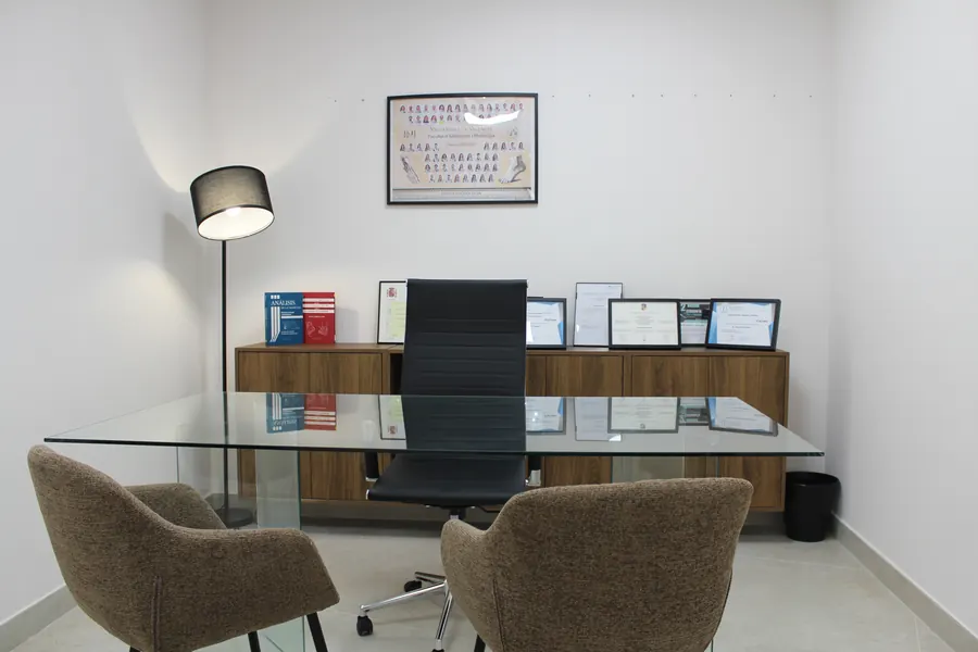 Despacho de consulta con mesa de cristal y diplomas