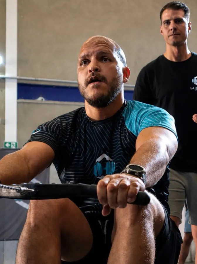 Deportista en un ejercicio de remo con público al fondo
